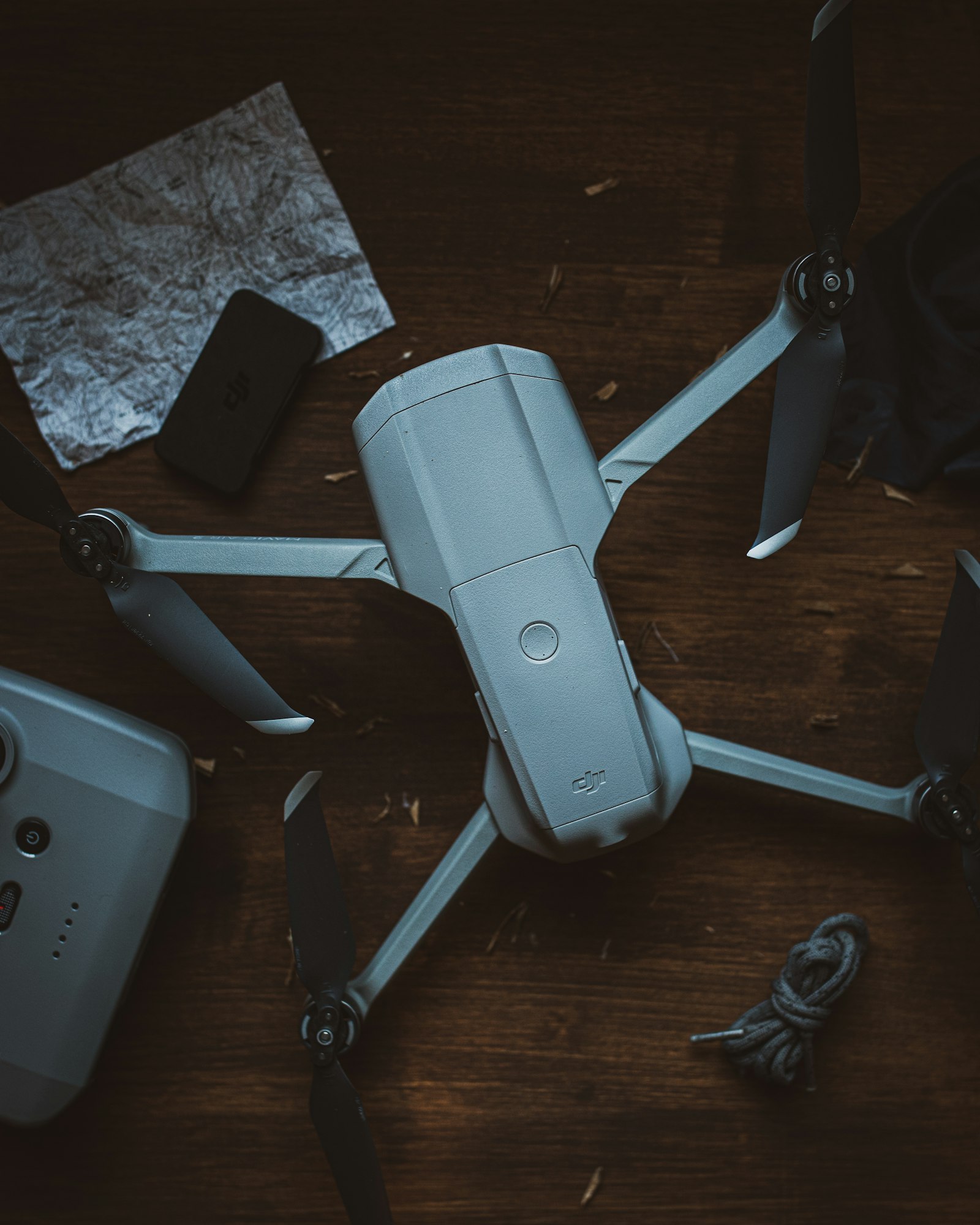 Dron plegado sobre una mesa junto a mapa, mando y accesorios de vuelo
